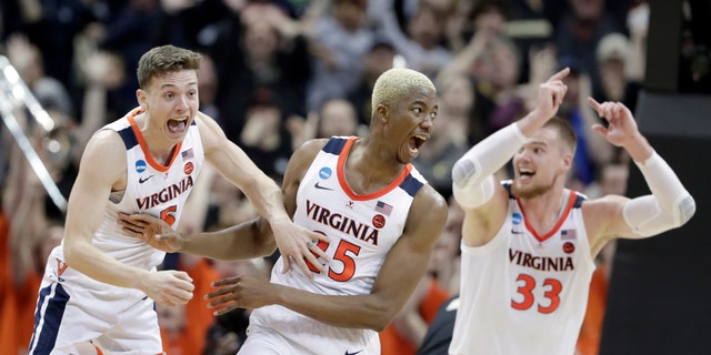 Virginia's Mamadi Diakite, center, reacts with teammates Kyle Guy and Jack Salt (33) after hitting a shot to send the game into overtime in the men's NCAA Tournament college basketball South Regional final game against Purdue, Saturday, March 30, 2019, in Louisville, Ky. (Associated Press)