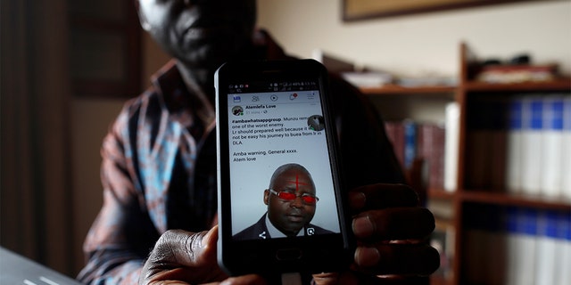 Simon Munzu, a former UN official, who is campaigning for peace in the Anglophone regions of Cameroon, shows a threat message posted against him on social media by separatists during an interview with Reuters in Yaounde, Cameroon.