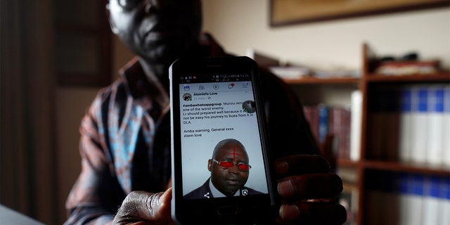 Simon Munzu, a former UN official, who is campaigning for peace in the Anglophone regions of Cameroon, shows a threat message posted against him on social media by separatists during an interview with Reuters in Yaounde, Cameroon.