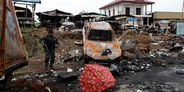 A Cameroonian elite Rapid Intervention Battalion (BIR) member walks past a burnt car while patrolling in the city of Buea in the anglophone southwest region, Cameroon October 4, 2018. Picture taken October 4, 2018.