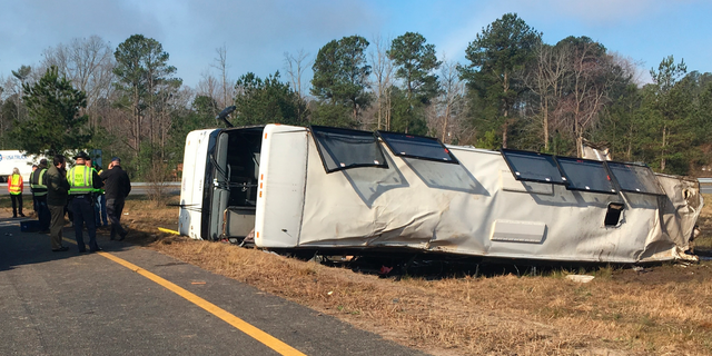 This photo provided by Virginia State Police emergency responders at the scene after a charter bus overturned on an Interstate 95 exit near Kingwood, Va., Tuesday. (Virginia State Police via AP)