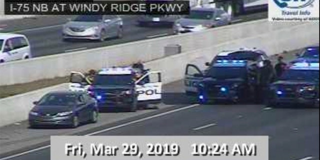 In this image made from video provided by the Georgia Department of Transportation, Marietta Police block southbound lanes on Interstate-75, near Marietta, Ga., North of Atlanta, Friday, March 29, 2019. Marietta police said in a brief statement that the southbound lanes of Interstate 75 were shut down Friday morning due to a motorist stopped on the freeway just northwest of Atlanta. Police described the motorist as a "non-compliant driver." (Georgia Department of Transportation via AP)
