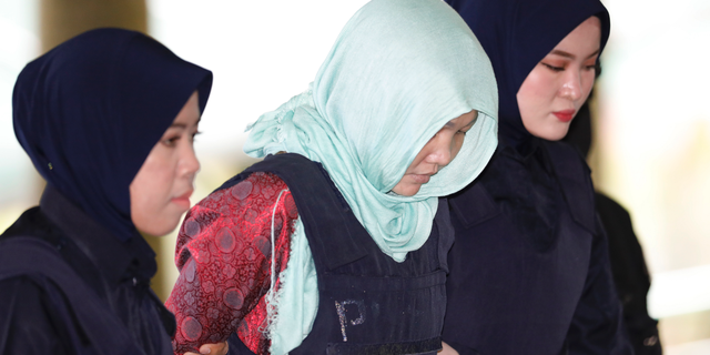 Vietnamese Doan Thi Huong, center, is escorted by police as she arrives at Shah Alam High Court in Shah Alam, Malaysia, Monday, April 1, 2019. Trial resumes on murder case against the Vietnamese woman accused in the killing of the North Korean leader's estranged half brother Kim Jong Nam. Prosecutors refused to drop the murder charge against Huong, who is the only suspect in custody after the stunning decision to drop the case against Indonesian Siti Aisyah.(AP Photo/Vincent Thian)