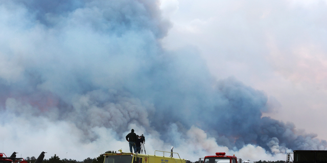 Spectators watch as the Spring Hill fire and backfire burns in Woodland Township, N.J., Sunday, March, 31, 2019. Authorities say fire whipped by high winds has spread over thousands of acres of state forest land in the Pinelands of New Jersey. (Ed Murray/NJ Advance Media via AP)