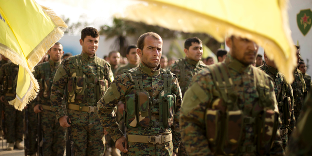 U.S.-backed Syrian Democratic Forces (SDF) stand in formation at a ceremony to mark their defeat of Islamic State militants in Baghouz, at al-Omar Oil Field base, Syria, Saturday, March 23, 2019. (AP Photo/Maya Alleruzzo)