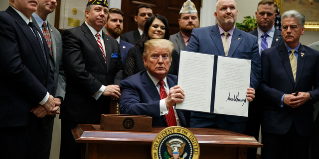 President Trump displays his signed executive order establishing a "National Roadmap to Empower Veterans and End Veteran Suicide" in March 2019. (AP Photo/ Evan Vucci)