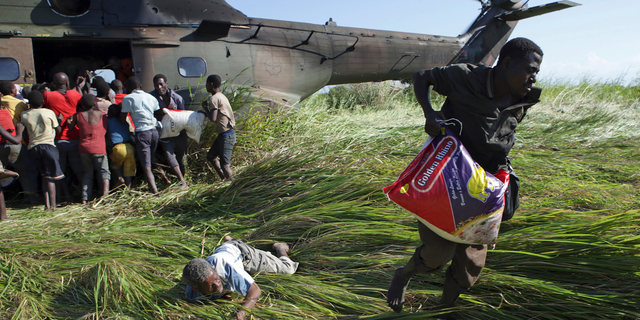 In this Tuesday, March 26, 2019, photo, an elderly man lies on the ground after his bag of food was snatched from him in a scramble for bags of rice delivered by the South African Airforce helicopter at Nyamatande Village, Mozambique, following the devastating Tropical Cyclone Idai. A second week has begun with efforts to find and help some tens of thousands of people in devastated parts of southern Africa, with some hundreds dead and an unknown number of people still missing. (AP Photo/Phill Magakoe)