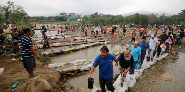 Las personas cruzan el río Táchira hacia Colombia, cerca del puente internacional Simón Bolívar, que las autoridades venezolanas solo abren a estudiantes y enfermos, en Cucuta, Colombia, el martes 12 de marzo de 2019, en la frontera con Venezuela. Las personas que cruzan el río están utilizando puentes improvisados a medida que el nivel del agua crece a medida que se acerca la temporada de lluvias. (Foto AP / Schneyder Mendoza)