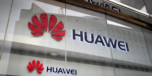 FILE - In this Jan. 29, 2019, file photo, the logos of Huawei are displayed at its retail shop window reflecting the Ministry of Foreign Affairs office in Beijing. (AP Photo/Andy Wong, File)