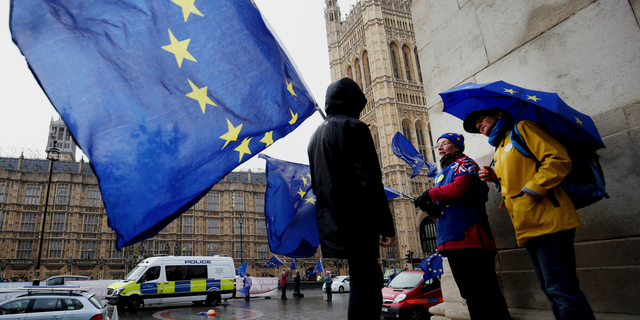Remain supporters shelter from the wind and rain across the street from parliament in London, Thursday, Feb. 28, 2019. (Jonathan Brady/PA via AP)
