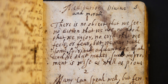In this Wednesday, March 20, 2019, photo provided by the Board of Trustees of Stevens Memorial Library, a handwritten manuscript called "Meditations Divine and Moral," by 17th century poet Anne Bradstreet, rests on a table at the Houghton Library on the campus of Harvard University, in Cambridge, Mass. Bradstreet was the North American continent's first published poet. Her actual burial place is not known. (Courtesy of Board of Trustees of Stevens Memorial Library via AP)
