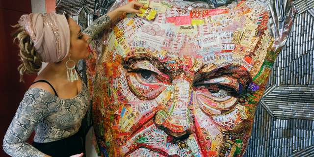 Ukrainian artist Dasha Marchenko adds a chocolate wrapper to her portrait of Ukraine's President and chocolate tycoon Petro Poroshenko at her studio in Kiev, Ukraine, Thursday, March 28, 2019. (AP Photo/Efrem Lukatsky)