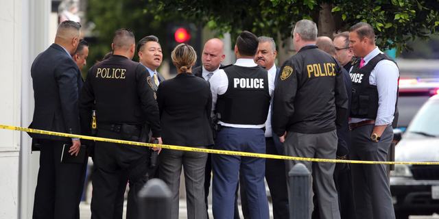 Investigators confer just down the street from the Church of Scientology after a shooting wounded two police officers and killed a sword-wielding suspect in Inglewood, Calif., on Wednesday. (Associated Press)