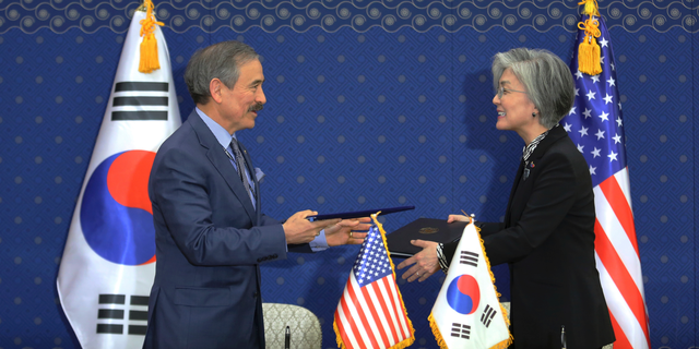 South Korean Foreign Minister Kang Kyung-wha, right, and U.S. Ambassador to South Korea Harry Harris exchange documents at Foreign Ministry in Seoul, South Korea, Friday, March 8, 2019. South Korea and the United States have formally signed a deal that increases Seoul's financial contribution for the deployment of U.S. troops in the Asian country. (AP Photo/Ahn Young-joon, Pool)