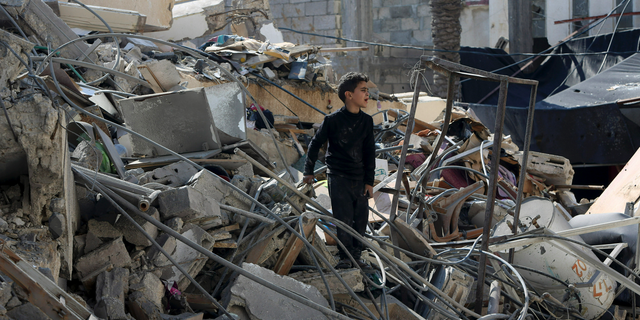 A Palestinian boy searches for their family's belongings amid the rubble of a destroyed building near a Hamas security building that was destroyed in an Israeli airstrike late Monday, in Gaza City, Wednesday, March 27, 2019. (AP Photo/Adel Hana)