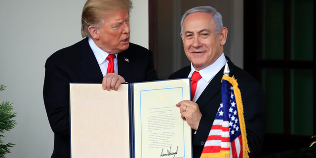 Visiting Israeli Prime Minister Benjamin Netanyahu and President Donald Trump hold up the signed proclamation recognizing Israel's sovereignty over the Golan Heights as Netanyahu leaves the White House in Washington, Monday, March 25, 2019. (AP Photo/Manuel Balce Ceneta)
