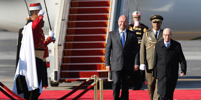Iraq's President Barham Salih, left, walks next of his Tunisian counterpart Beji Caid Essebsi, right, as they review the honor guard upon his arrival at Tunis-Carthage international airport to attend the Arab Summit, in Tunis, Tunisia, Saturday, March 30, 2019. (AP Photo/Hussein Malla, Pool)