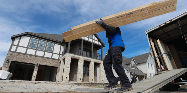 FILE- In this Feb. 20, 2019, file photo a worker carries interior doors to install in a just completed new home in north Dallas. On Tuesday, March 26, the Commerce Department reports on U.S. home construction in February. (AP Photo/LM Otero, File)