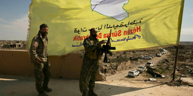 U.S.-backed Syrian Democratic Forces (SDF) fighters pose for a photo on a rooftop overlooking Baghouz, Syria, after the SDF declared the area free of Islamic State militants after months of fighting on Saturday, March 23, 2019. The elimination of the last Islamic State stronghold in Baghouz brings to a close a grueling final battle that stretched across several weeks and saw thousands of people flee the territory and surrender in desperation, and hundreds killed. (AP Photo/Maya Alleruzzo)