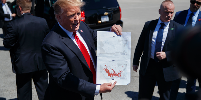 FILE - In this March 22, 2019, photo, President Donald Trump holds a a copy of two maps of Syria as he arrives on Air Force One, Friday, March 22, 2019, at Palm Beach International Airport, in West Palm Beach, Fla. There was just one problem when Trump walked down the stairs of Air Force One and unceremoniously declared that the Islamic State had lost the last of its territory in Syria. He wasn’t supposed to announce it yet. (AP Photo/Carolyn Kaster)