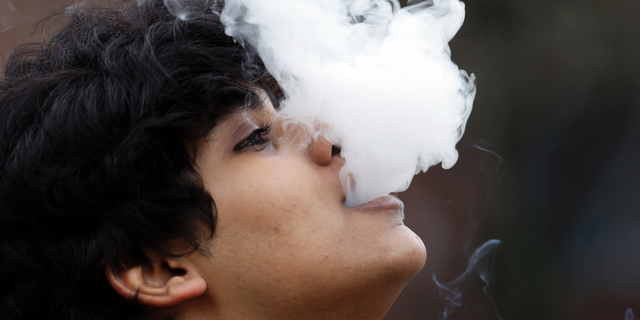 FILE - In this Jan. 7, 2016, file photo, a man who declined to be identified blows out a cloud of smoke as he puffs on a small pipe outside at Seattle Central College in Seattle. A proposal to raise Washington's smoking and vaping age to 21 has passed the Legislature on Wednesday, March 27, 2019, putting the state on the precipice of becoming the ninth state to make such a change. The Texas Senate approved a similar bill that would raise the legal age to buy and use tobacco products from 18 to 21, exempting active U.S. military members from the age raise.