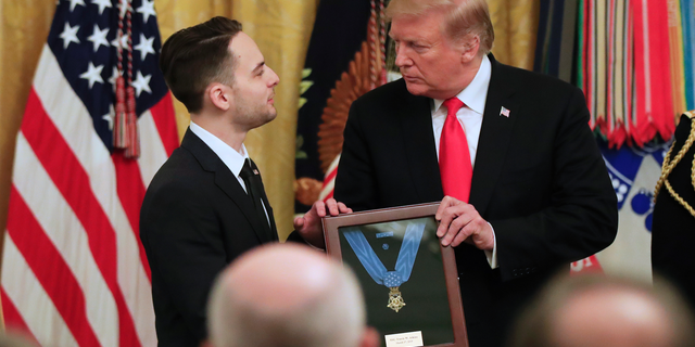 Trevor Oliver accepts the Medal of Honor from President Donald Trump, presented to his father, Army Staff Sgt. Travis Atkins in recognition for conspicuous gallantry in Iraq in June 2007, during a ceremony in the East Room of the White House, Wednesday March 27, 2019, in Washington.(AP Photo/Manuel Balce Ceneta)