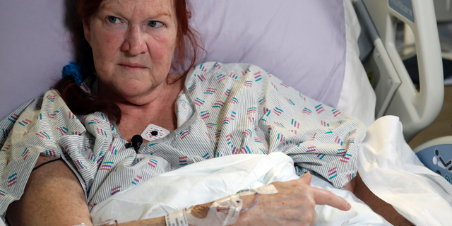 Deborah Judd, 56, sits in her hospital bed at Harborview Medical Center and talks about the injuries she suffered in a shooting a day earlier, Thursday, March 28, 2019, in Seattle. The afternoon shooting spree and carjacking in Seattle left two people dead and two injured. (AP Photo/Elaine Thompson)