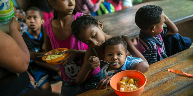 Eight-year-old Franyelis feeds her baby brother Joneiber as their mother Francibel Contreras holds a bowl of scrambled eggs and rice, at a soup kitchen in the Petare slum, Caracas, Venezuela. Contreras brings her three malnourished children to the soup kitchen in the dangerous hillside slum where they scoop in spoonfuls of food in what could be their only meal of the day. (AP Photo/Rodrigo Abd)