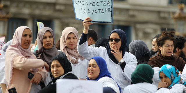 An Algerian woman holds a placard that reads, 'we need to disinfect the system' during a protest in Algiers, Algeria, Tuesday, March 19, 2019. (AP Photo/Anis Belghoul)