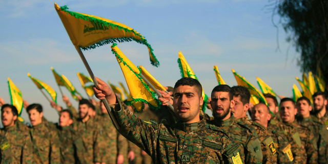 In this Feb. 13, 2016 file photo, Hezbollah fighters hold flags as they attend the memorial of their slain leader Sheik Abbas al-Mousawi, who was killed by an Israeli airstrike in 1992.