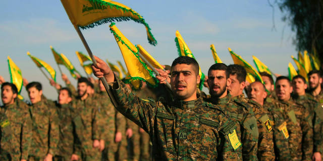 Hezbollah fighters hold flags as they attend the memorial for their slain leader Sheikh Abbas al-Mousawi.