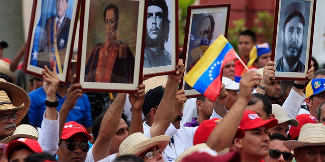 Cuban doctors hold up framed pictures (L-R) of late President Hugo Chavez, Venezuela's National hero Simon Bolivar, Ernesto 'Che' Guevara, Cuban national hero Jose Marti and Fidel Castro during a march of farmers in support of Venezuela's President Nicolas Maduro in Caracas February 26, 2014. REUTERS/Tomas Bravo