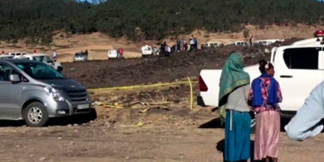 In this image taken from video, people stand around the crash site of an Ethiopian Airlines flight that crashed shortly after takeoff lies at the scene at Hejere near Bishoftu, or Debre Zeit, some 31 miles south of Addis Ababa, in Ethiopia Sunday, March 10, 2019.