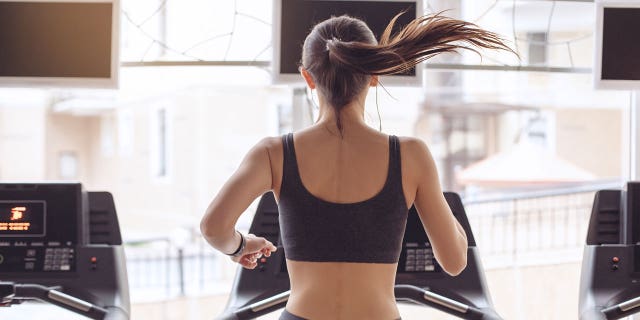Een vrouw loopt op een loopband in de sportschool.