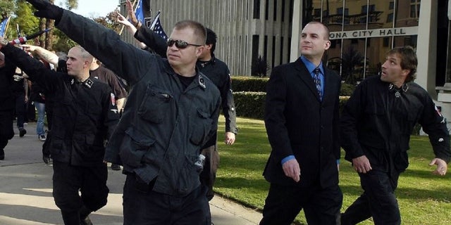 Jeff Schoep, second right on trial, commander of the National Socialist Movement, placed under police protection after a rally against illegal immigration in Pomona, California. (Thomas R. Cordova / Orange County Register via AP)