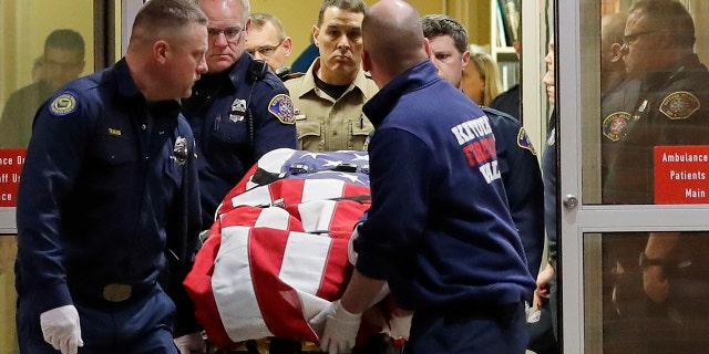 The body of Kittitas County sheriff's deputy Ryan Thompson is draped with a U.S. flag as it is carried out of Kittitas Valley Healthcare Hospital in the early morning hours of Wednesday, March 20 in Ellensburg, Wash. (Associated Press)