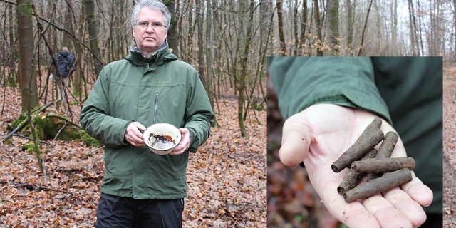 Cartridge cases and an enamel bowl found at one of the massacre sites are shown by Dr. Marcus Weidner, a historian at the LWL Institute for Westphalian Regional History.