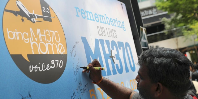A man writes a condolence message during a Day of Remembrance for MH370 event in Kuala Lumpur, Malaysia, Sunday, March 3, 2019.