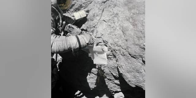 Duke examines the surface of a large lunar boulder during the Apollo 16 mission. (NASA)