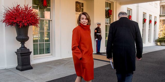 Pelosi speaks to a reporter as she and Chuck Schumer walk back into the West Wing after speaking to members of the media outside of the White House in Washington on Dec. 11, 2018, following a meeting with President Donald Trump.