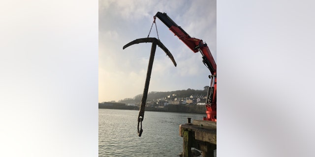 The fishing crew who netted the anchor from what might be the world's most valuable shipwreck display their find. (SWNS)