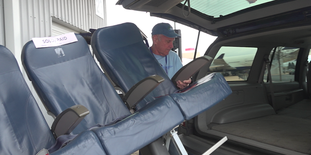 Volunteers load a set of airplane seats into a shopper's trunk at the Delta Surplus Sale.