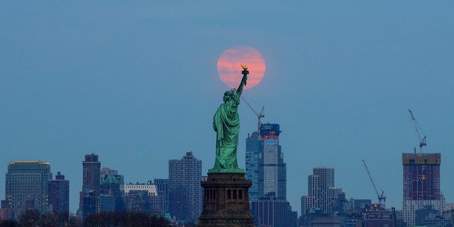 The last supermoon of 2019 rises behind the Statue of Liberty in New York, United States, on March 20, 2019.