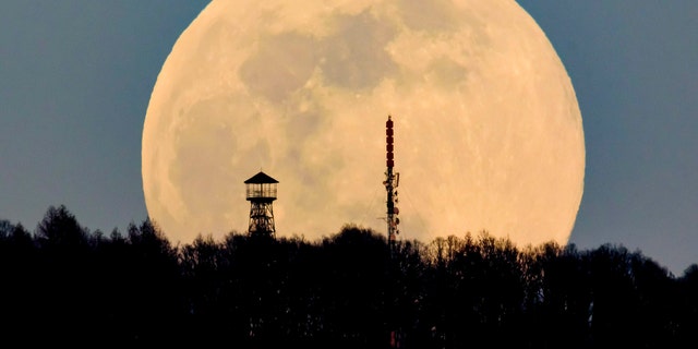 A watchtower, on the left, and the Antenna Hungaria television tower on top of Karancs mountain are suspended from the rising moon, seen from the village of Karancskeszi, 128 km northeast of Budapest, Hungary, on Wednesday. March 2019.