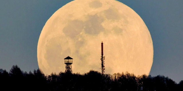 A lookout tower, left, and the broadcast tower of Antenna Hungaria at the top of Karancs mountain are backdropped by the rising moon as seen from the vicinity of Karancskeszi village, 128 kms northeast of Budapest, Hungary, Wednesday, March 20, 2019.