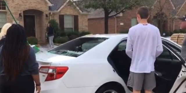 Residents in Frisco work to scoop hail out of the back of a car after windows were shattered during a hailstorm on Sunday.