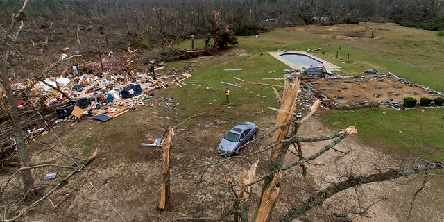 Debris from a home litters a yard the day after a tornado blew it off its foundation, at right, in Beauregard, Ala., Monday, March 4, 2019.