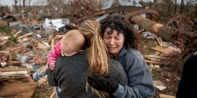 Carol Dean, right, cries while embraced by Megan Anderson and her 18-month-old daughter Madilyn, as Dean sifts through the debris of the home she shared with her husband, David Wayne Dean, who died when a tornado destroyed the house in Beauregard, Ala., Monday, March 4, 2019.