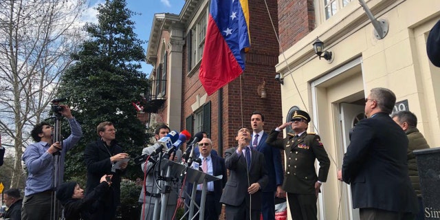 Juan Guaido's ambassador to the U.S., Carlos Vecchio, raising a Venezuelan flag outside a building belonging to Venezuela's defense ministry Monday in Washington, D.C.