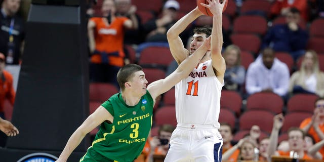 Virginia's Ty Jerome (11) is fouled by Oregon's Payton Pritchard (3) during the second half of a men's NCAA Tournament college basketball South Regional semifinal game. (Associated Press)